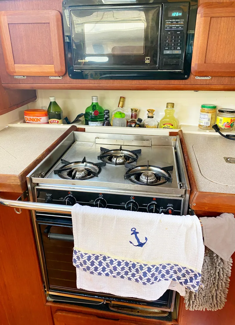 Slide: The Image of 1997 Hunter 430 yacht kitchen with stove, microwave, and nautical-themed towel. - 16