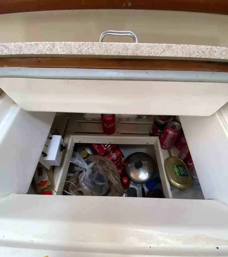 Slide: The Image of Storage compartment in a 1997 Hunter 430 yacht, filled with cans and kitchen items. - 19