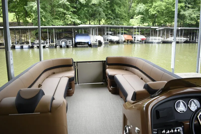 Slide: The Image of 2024 Avalon Catalina Funship 25' pontoon boat interior with tan seating, docked at a marina. - 10