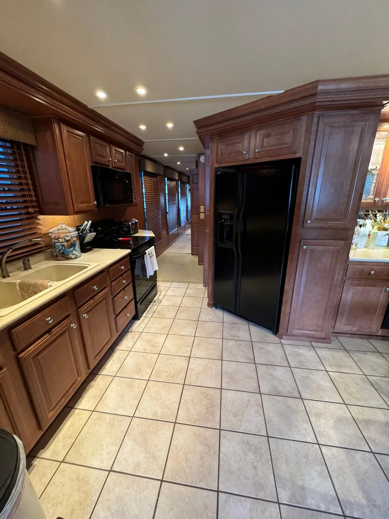 Slide: The Image of 2003 Sharpe 75' Houseboat kitchen with wooden cabinets and black appliances. - 23