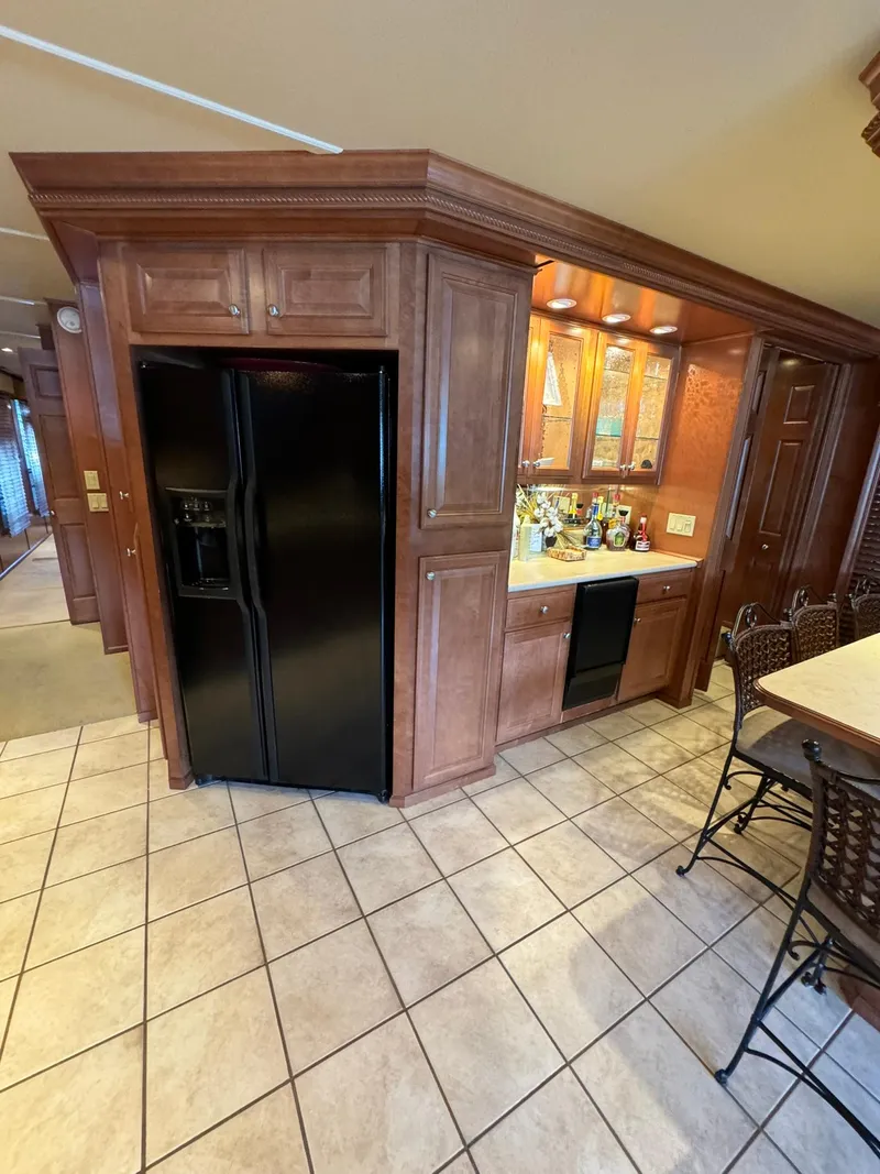 Slide: The Image of 2003 Sharpe 75' Houseboat kitchen with black refrigerator and wooden cabinetry. - 24