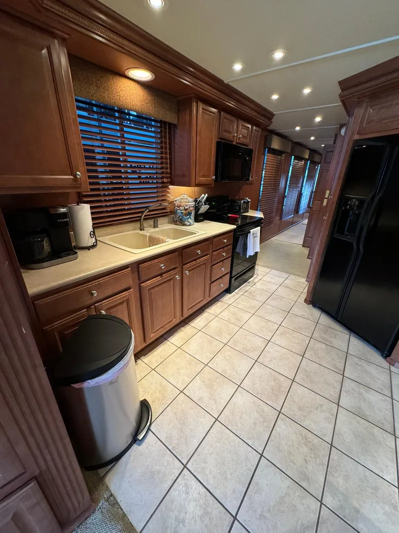 Slide: The Image of 2003 Sharpe 75' Houseboat kitchen with wooden cabinets, tiled floor, and modern appliances. - 27