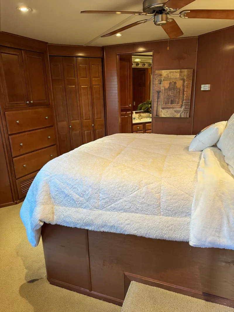 Slide: The Image of Bedroom interior of a 2003 Sharpe 75' Houseboat with wooden cabinetry and a ceiling fan. - 28