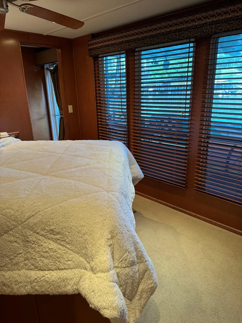 Slide: The Image of Bedroom interior of a 2003 Sharpe 75' Houseboat with large windows and cozy bedding. - 31