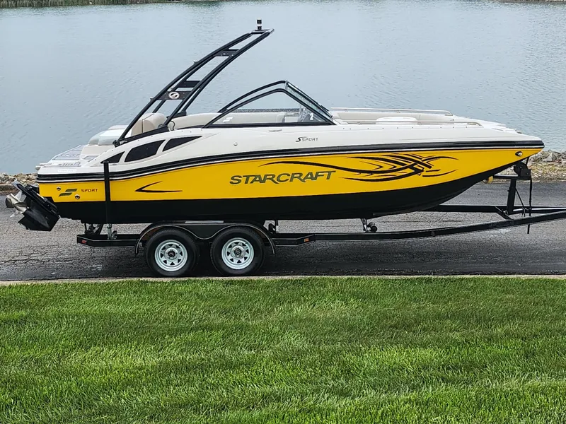 Slide: The Image of 2015 Starcraft Crossover 210 SCX IO boat on trailer by a lake. - 0