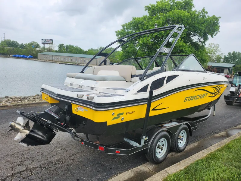 Slide: The Image of 2015 Starcraft Crossover 210 SCX IO boat on trailer by a lake. - 1