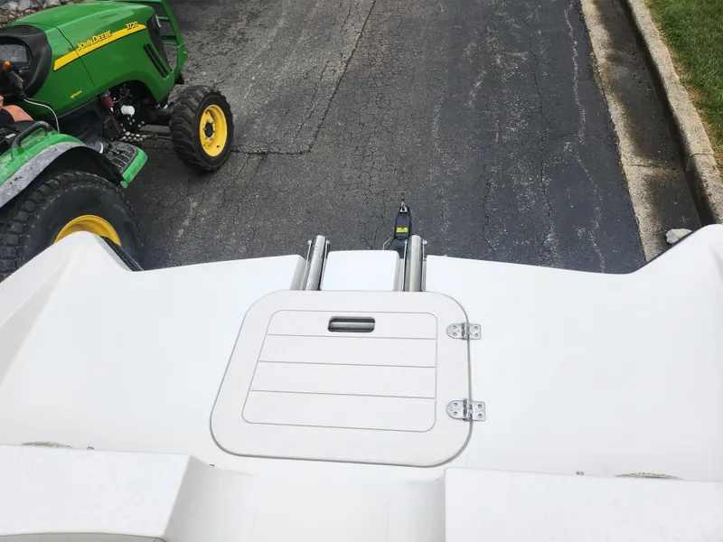 Slide: The Image of 2015 Starcraft Crossover 210 SCX IO boat rear view with a green tractor nearby. - 16