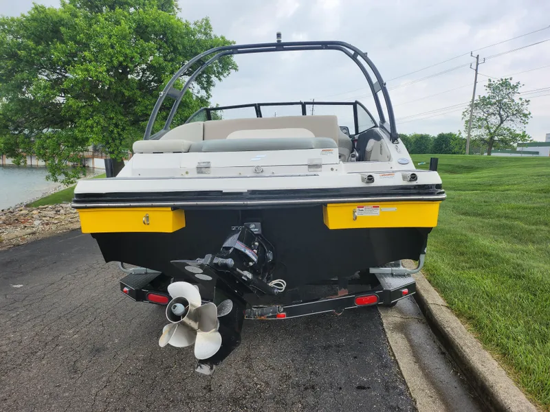 Slide: The Image of 2015 Starcraft Crossover 210 SCX IO boat, rear view, on a trailer near a lake. - 2