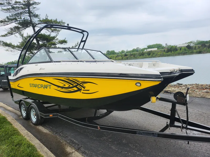 Slide: The Image of 2015 Starcraft Crossover 210 SCX IO boat on trailer by a lake. - 8