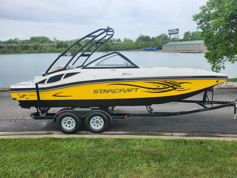 Slide: The Image of 2015 Starcraft Crossover 210 SCX IO boat on trailer by a lake. - 9