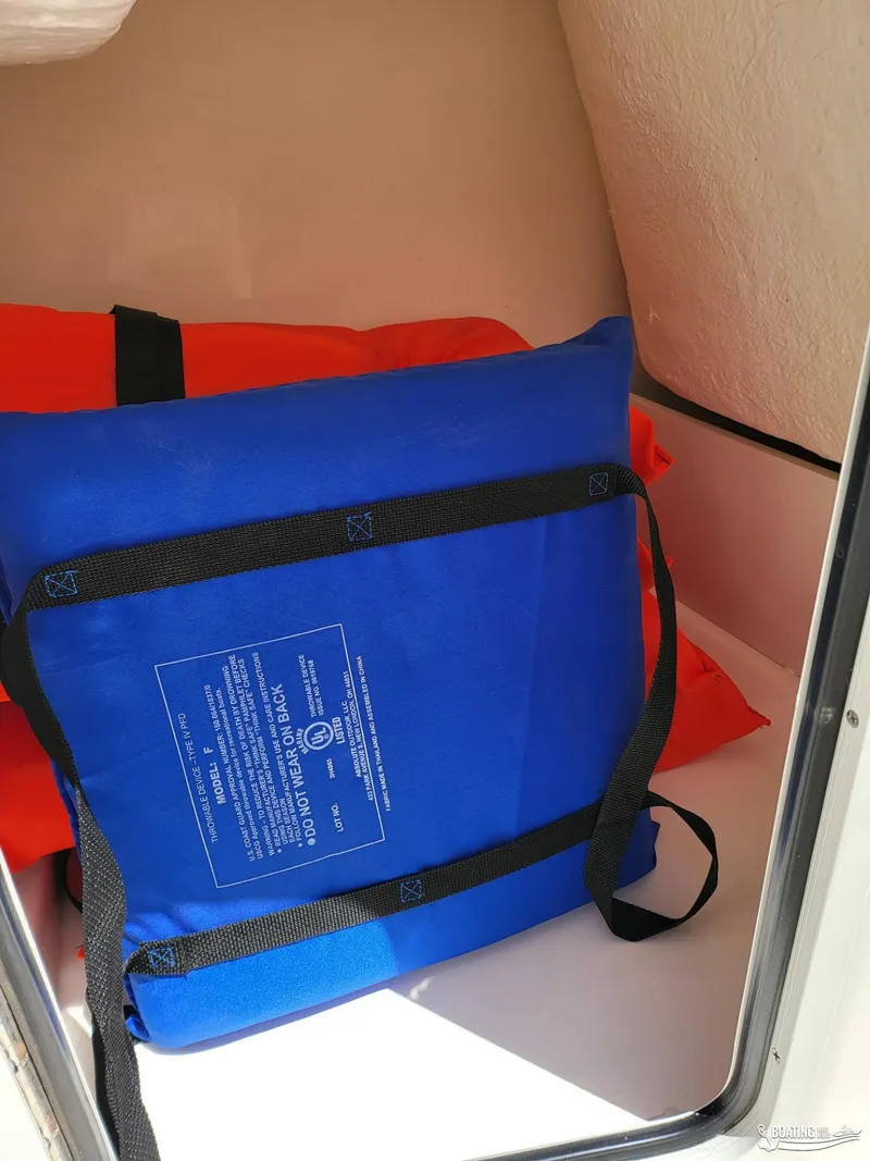 Slide: The Image of Blue and orange life jackets stored in a 2021 Bayliner E 21 boat compartment. - 11