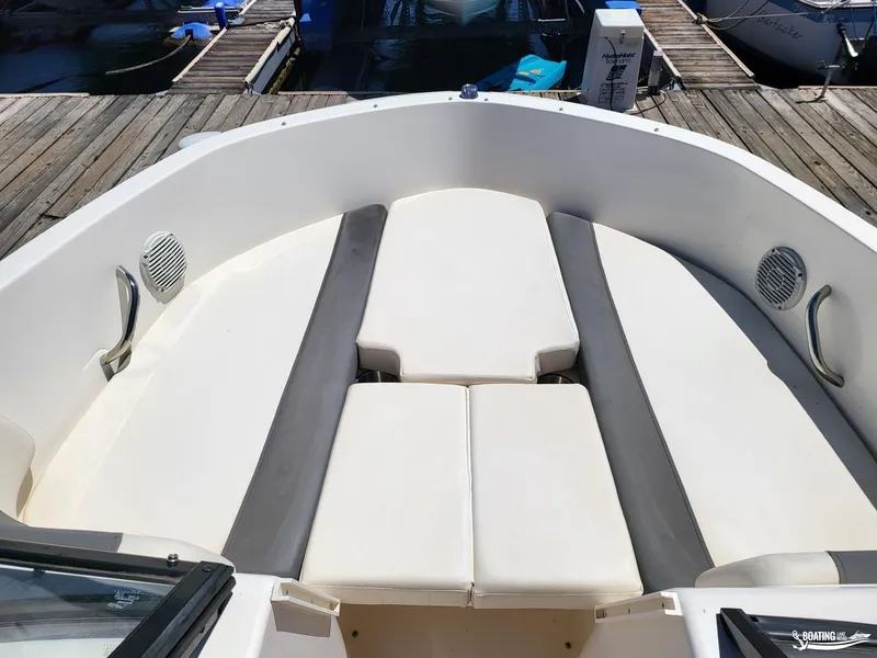 Slide: The Image of 2021 Bayliner E 21 boat interior with cushioned seating at the dock. - 5
