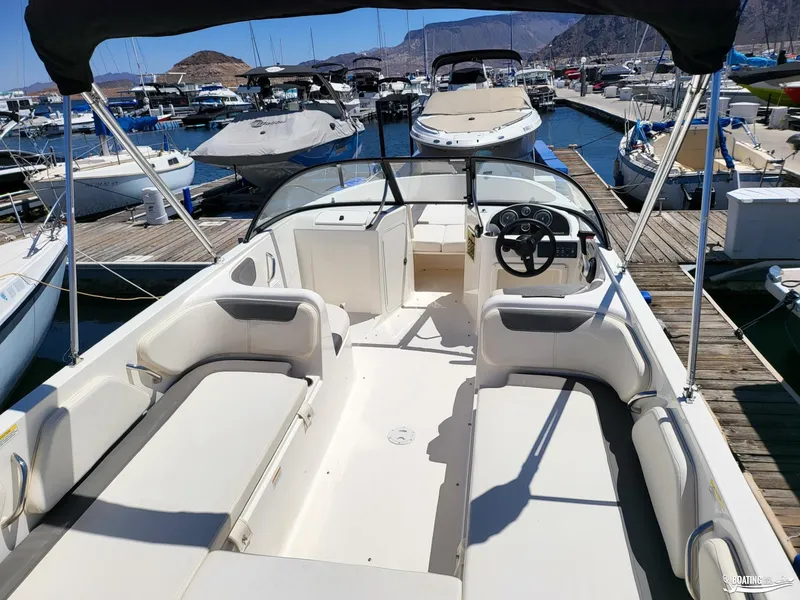 Slide: The Image of 2021 Bayliner E 21 boat interior at marina, featuring spacious seating and steering console. - 8