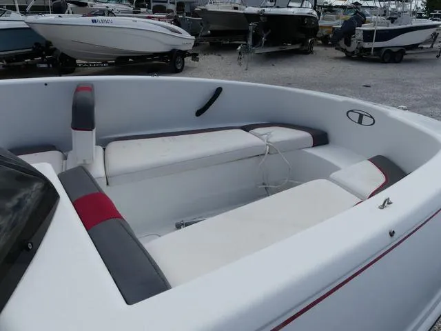 Slide: The Image of 2021 Tahoe T16 boat interior with white and red seating, parked among other boats. - 8