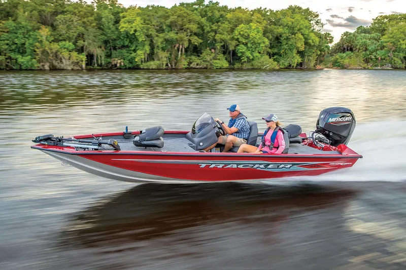 Slide: The Image of 2024 Tracker Pro Team 175 TXW boat speeding on a river with two passengers. - 2