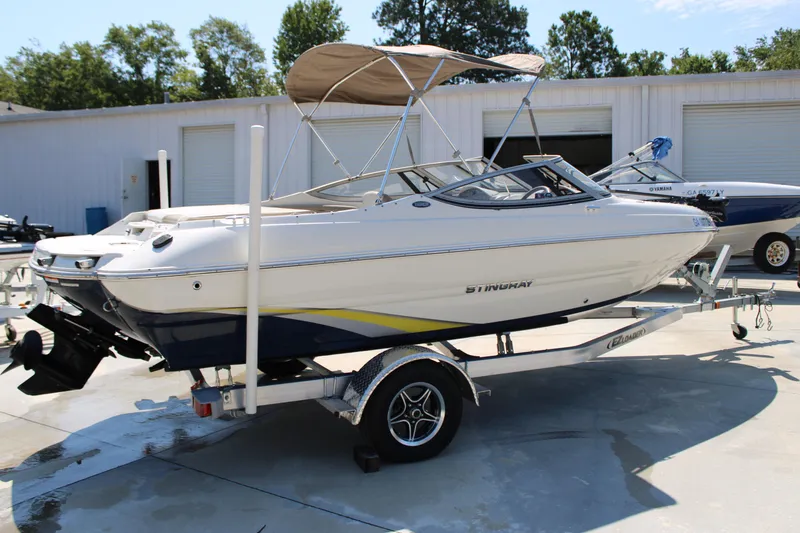 Slide: The Image of 2014 Stingray 198 LF boat on trailer, parked outdoors near storage facility. - 14