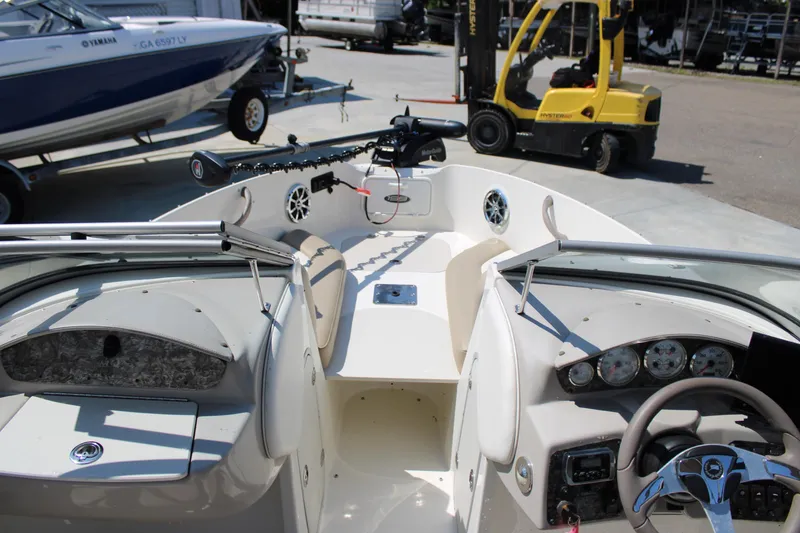 Slide: The Image of 2014 Stingray 198 LF boat interior with steering wheel and dashboard, parked near forklift. - 21