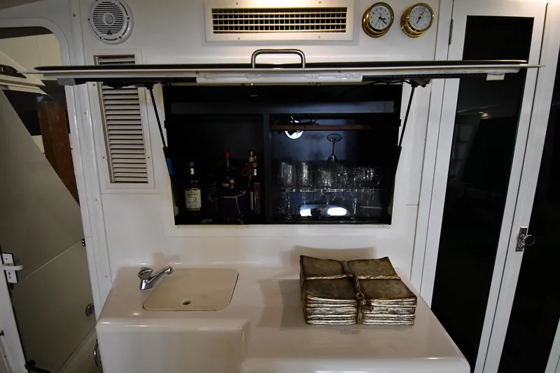Slide: The Image of 1997 Viking 60 Cockpit Sport Yacht interior with bar, sink, and vintage books. - 31