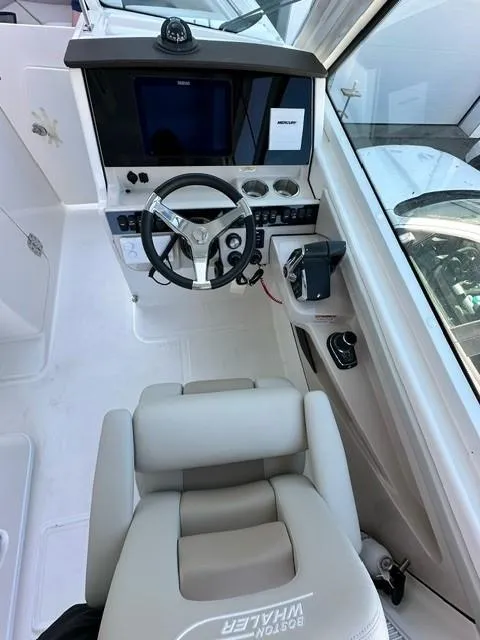 Slide: The Image of 2023 Boston Whaler 280 Vantage helm station with steering wheel and navigation controls. - 23