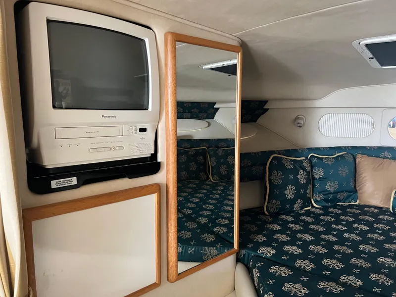 Slide: The Image of 1997 Sea Ray 330 Sundancer cabin interior with TV, mirror, and patterned seating. - 10