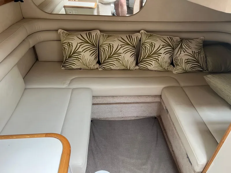 Slide: The Image of 1997 Sea Ray 330 Sundancer cabin with beige seating and tropical leaf pillows. - 11