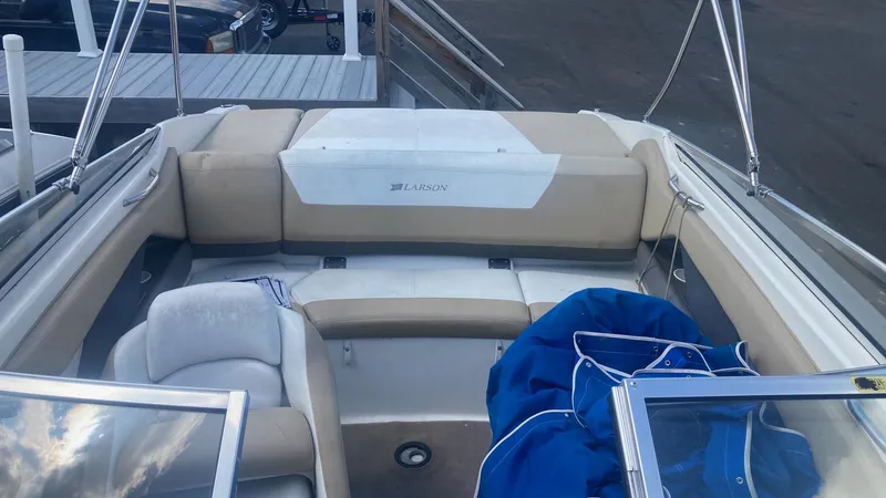 Slide: The Image of 2005 Larson 208LXi boat interior with beige seating and blue cover. - 2