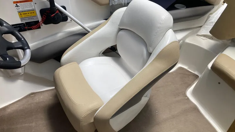 Slide: The Image of Captain's seat in a 2005 Larson 208LXi boat, featuring beige and white upholstery. - 8