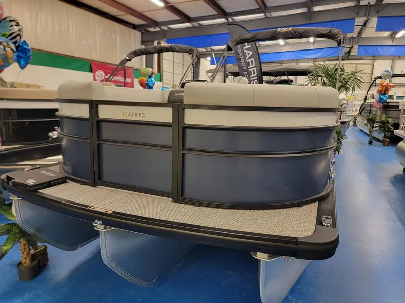Slide: The Image of 2024 Harris Cruiser 230 pontoon boat on display in a showroom. - 0