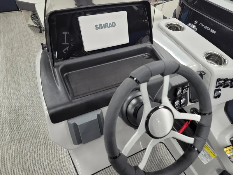 Slide: The Image of 2024 Harris Cruiser 230 boat dashboard with Simrad display and steering wheel. - 10