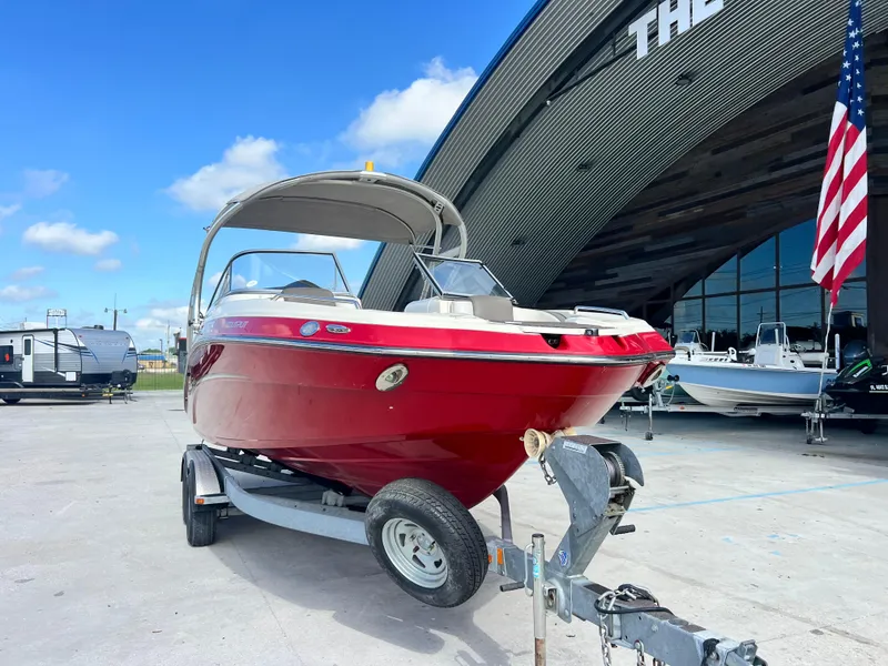 Slide: The Image of Red 2014 Yamaha Boats 242 Limited S on trailer, parked outside dealership. - 2