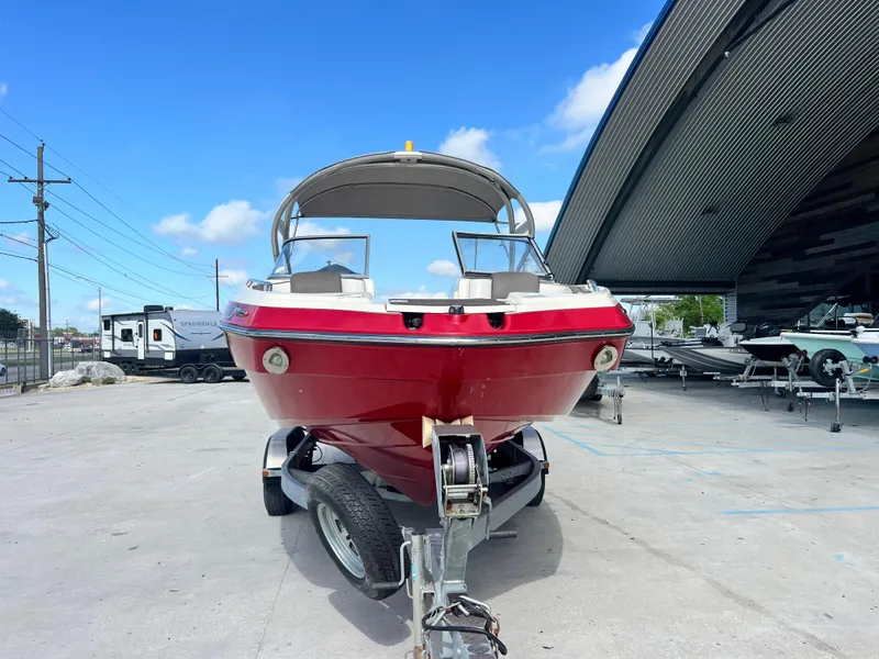 Slide: The Image of 2014 Yamaha Boats 242 Limited S in red, parked on a trailer under a blue sky. - 3