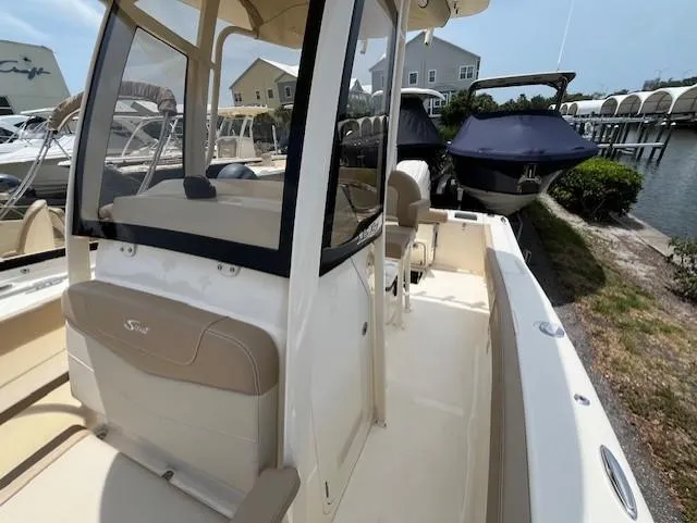 Slide: The Image of 2024 Scout 215XSF boat docked at a marina, showcasing its interior and helm. - 10