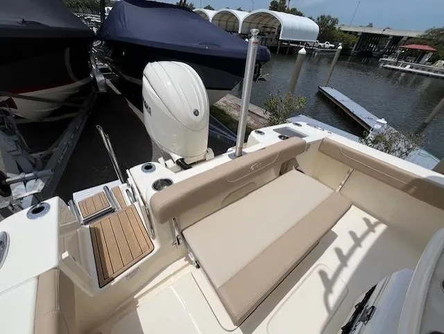Slide: The Image of 2024 Scout 215XSF boat with beige seating and outboard motor docked at marina. - 16