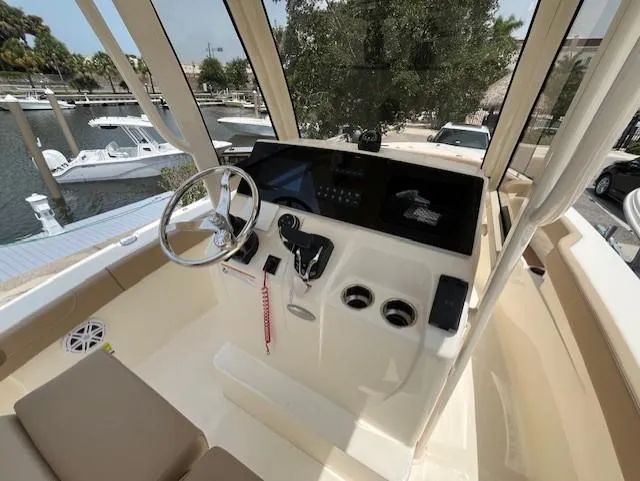 Slide: The Image of 2024 Scout 215XSF boat helm with steering wheel and control panel, docked at marina. - 7