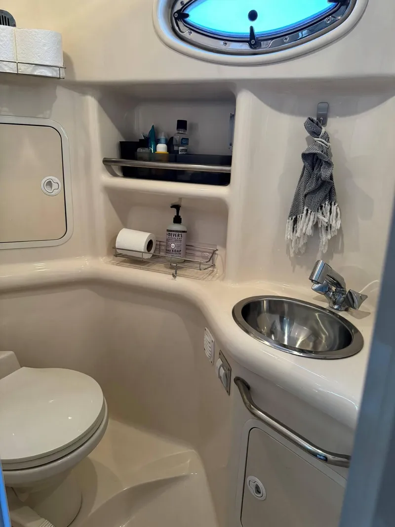 Slide: The Image of Compact bathroom in 2002 Sea Ray 310 Sundancer with toilet, sink, and storage shelves. - 5