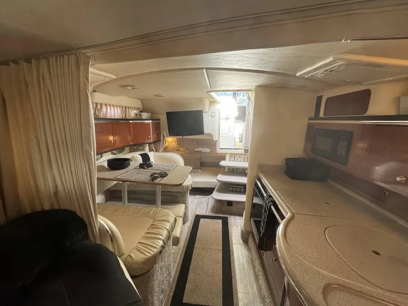 Slide: The Image of Interior of 2002 Sea Ray 310 Sundancer yacht with kitchen, dining area, and TV. - 8