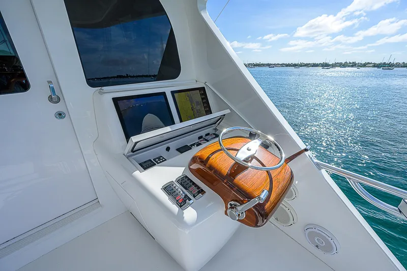 Slide: The Image of 2018 Viking 92 Sky Bridge helm station with dual screens and wooden steering wheel. - 36