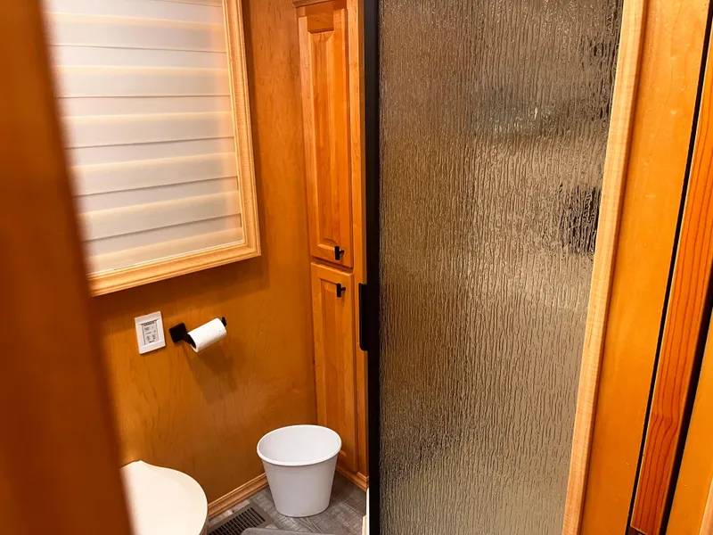 Slide: The Image of 2004 Starlight 68X16 bathroom with wooden cabinets, frosted glass shower, and white waste bin. - 16