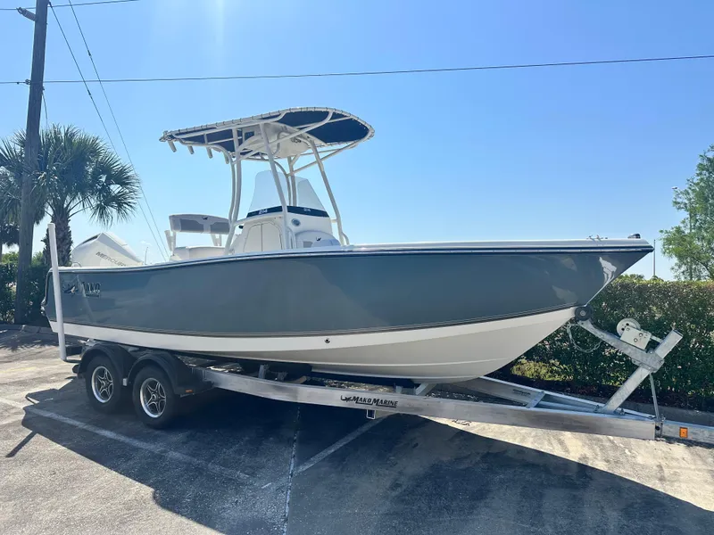 The Image of 2024 Mako 214 CC boat on trailer, parked outdoors under clear blue sky. - 0