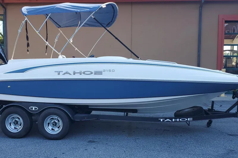 Slide: The Image of 2024 Tahoe 2150 boat with blue canopy on trailer, side view. - 0