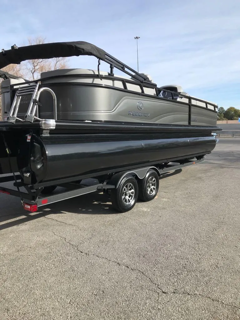 Slide: The Image of 2024 Regency 250 LE3 pontoon boat on trailer in parking lot. - 5