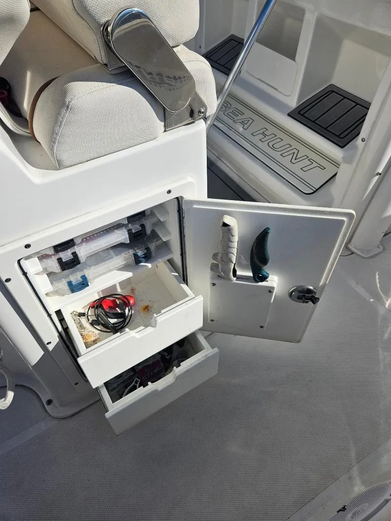 Slide: The Image of 2021 Sea Hunt Gamefish 25 boat storage compartment with open drawers and fishing gear. - 26