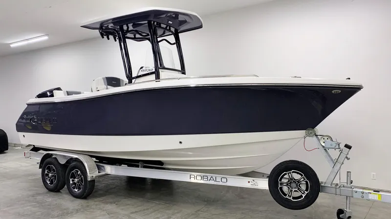 Slide: The Image of 2024 Robalo R232 Explorer boat on a trailer in a showroom. - 2