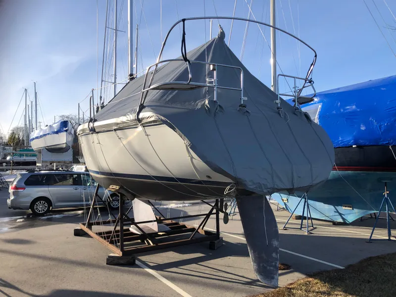 Slide: The Image of 1995 Catalina 320 sailboat covered and stored on a stand in a marina. - 13