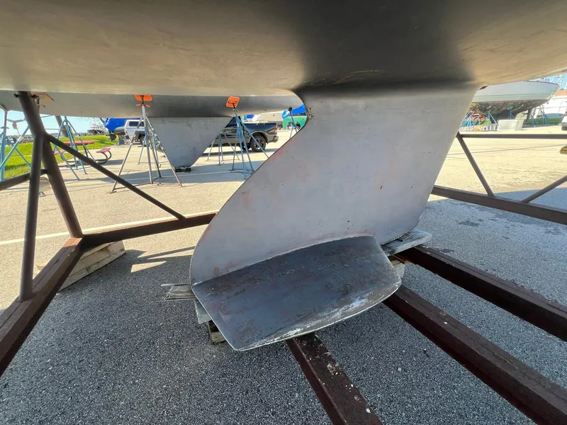 Slide: The Image of Catalina 320 sailboat keel and rudder, 1995 model, on a boatyard stand. - 16