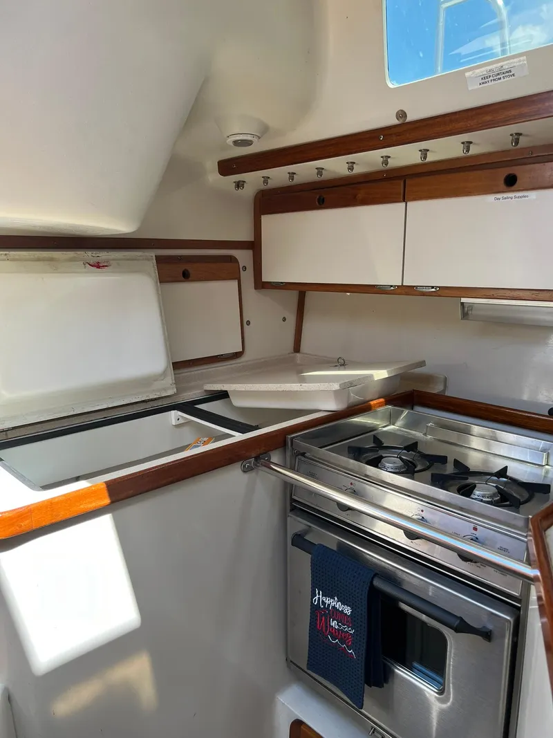 Slide: The Image of 1995 Catalina 320 sailboat kitchen with stove, sink, and storage cabinets. - 42