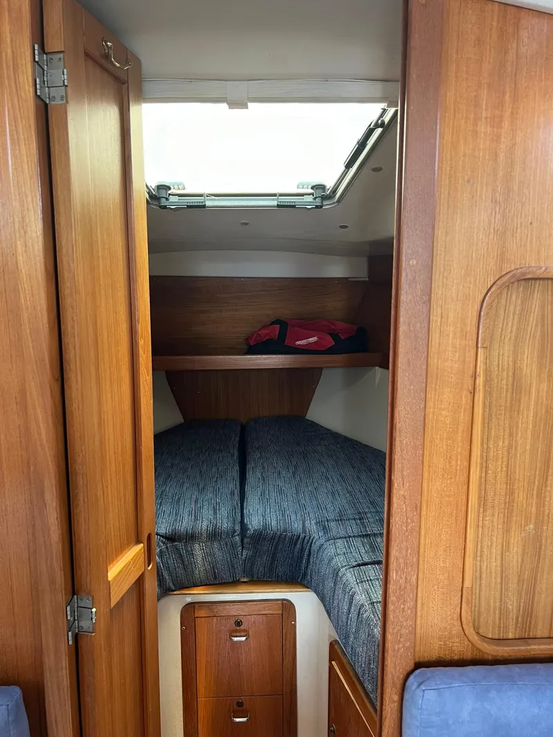 Slide: The Image of 1995 Catalina 320 sailboat cabin interior with wooden finish and cozy bedding. - 43