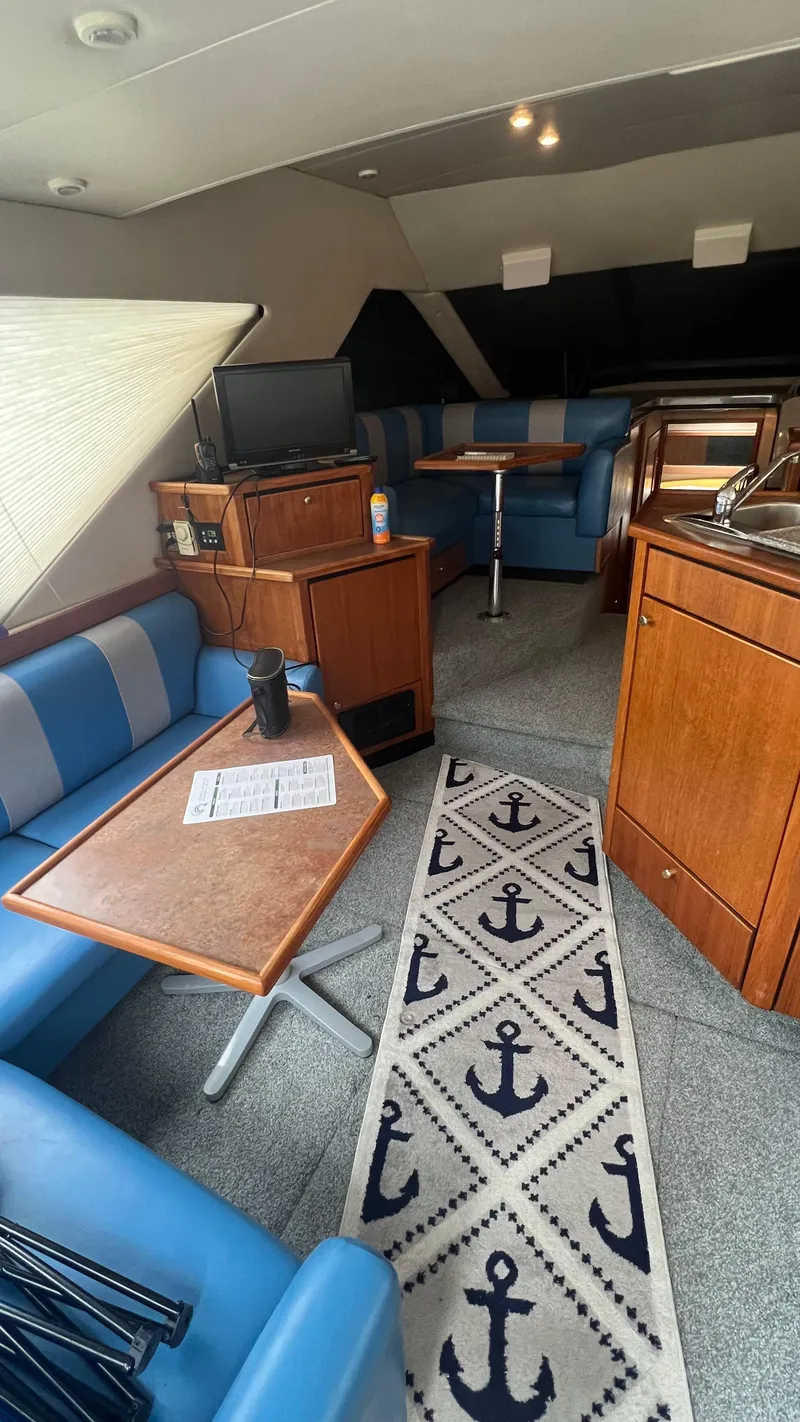 Slide: The Image of Interior of 1999 Bayliner 3988 Motoryacht with blue seating and anchor-themed rug. - 10