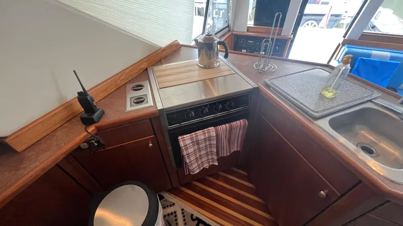 Slide: The Image of 1999 Bayliner 3988 Motoryacht kitchen with stove, sink, and countertop accessories. - 12