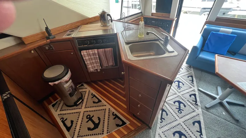 Slide: The Image of 1999 Bayliner 3988 Motoryacht kitchen with sink, stove, and nautical-themed decor. - 15